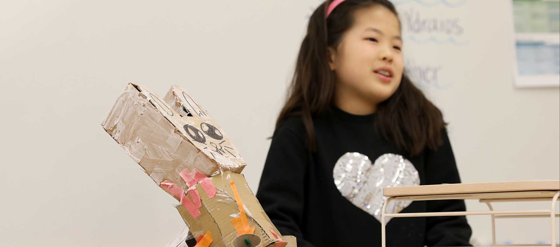 A girl presents her animal adaptation project for classmates